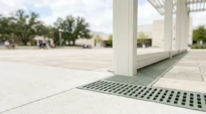 白色建築結構旁的格柵排水溝蓋與開闊廣場